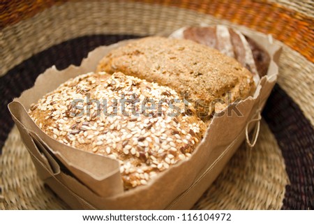 three types of bread, bread with caraway seeds, rye bread, bread with spices in a package with a bow on the background of wicker basket