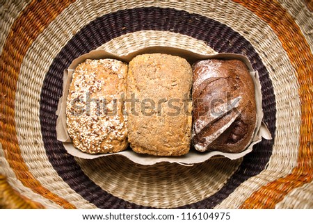 three types of bread, bread with caraway seeds, rye bread, bread with spices in a package with a bow on the background of wicker basket