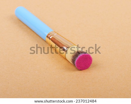 Makeup brush and cosmetic blush. On a beige background