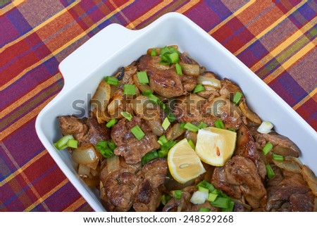 Fried chicken liver in a ceramic plate isolated on a checkered tablecloth, home cooking