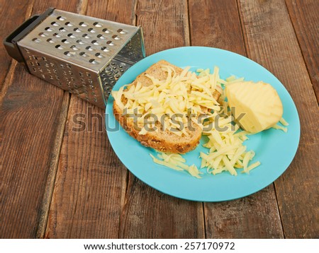 Grated cheese and grater on a plate on the table