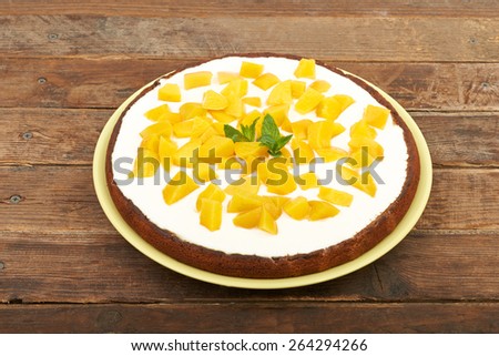 Coffee cake with butter cream and peach on a wooden table background