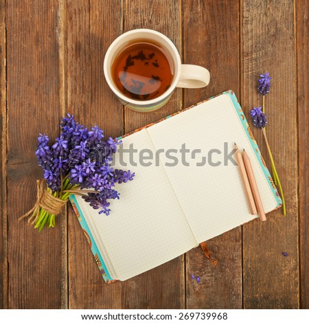 Notebook on a wooden table background with a bouquet of hyacinth flowers and a cup of tea