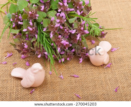 Herbs with lilac flowers and bird figurines on sacking canvas