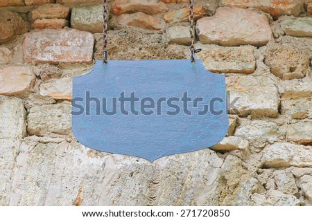 Old metal sign on the chains on the stone wall background