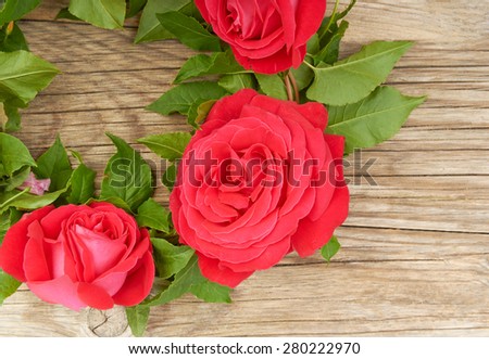 A wreath of red roses on the table wooden background