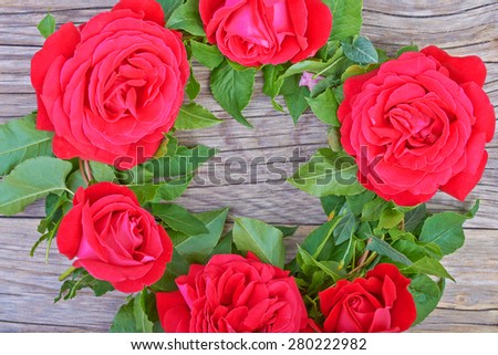 A wreath of red roses on the table wooden background