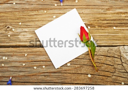 Bouquet of roses, spring flowers and blank sheet of paper on a table wooden background
