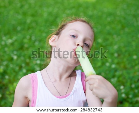 Adorable cute pretty little girl playing outdoors in summer and eating ice cream. Happy childhood.