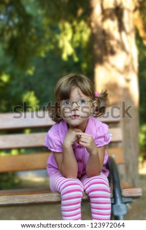 child with glasses sitting on  the bench , soft focus, best focus on the face, blurred background