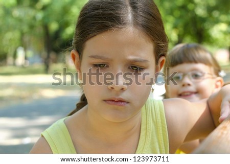 two girls in the park,best focus on the face of the first girl,child with glasses blurred, blurred background