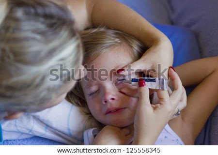 Mom puts the child in the eye cream,best focus on the eyes of the child and the mother\'s left hand,Blurred head mother