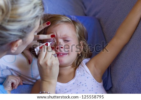 mother treated eye cream child,best focus on the child\'s face and left hand fingers mothers,Blurred head mother