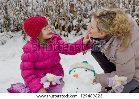 mother and daughter playing in the snow,best focus on the hair and lips mothers