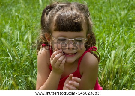 child sits in grass,best focus on the hair and right arm, blurred background