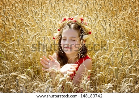 beautiful girl sits in the Rye and meditates,best focus on a child\'s face, hair and wheat in front of and next to the child,