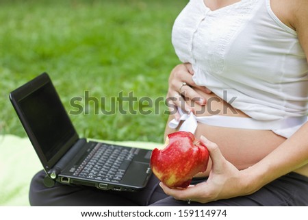 pregnant woman sitting and holding an apple in her hand, focus on the best apples and the left arm and fingers