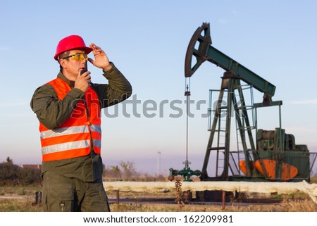 Oil Industry Pump jack with one oil worker who using a portable radio.