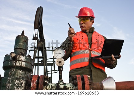 worker tells the radio station and holding laptop,best focus vest workers, head, glasses, helmets, laptops, pump oil soft focus