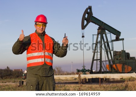 worker on an oil pump keeps the thumbs up and smiling,best focus on workers, oil pump soft focus