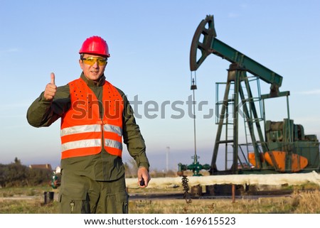 worker holding a thumbs-up and smiles, best focus on workers, oil pump soft focus