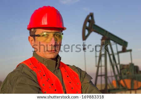 worker on an oil rig standing and looking at the camera, best focus on the man, background soft focus