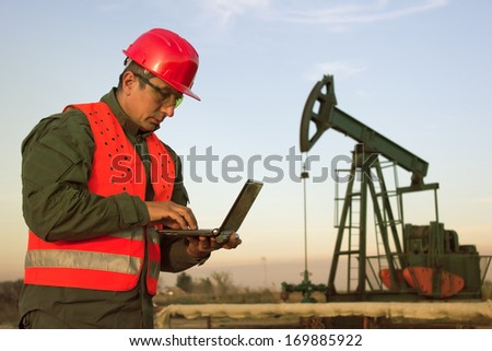 worker on an oil rig using a laptop, best focus on the man, background soft focus
