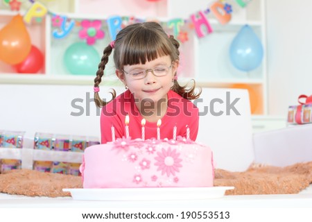 girl with glasses blows out the candles on the cake