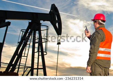 . Oil Industry Pump jack with one oil worker who using a portable radio