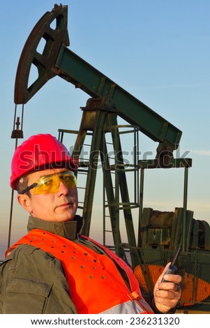 Oil Industry Pump jack with one oil worker who using a portable radio