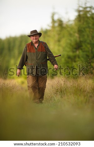hunter with his rifle in spring forest, hunter holding a rifle and  waiting for prey, hunter shooting, gamekeeper on the walk