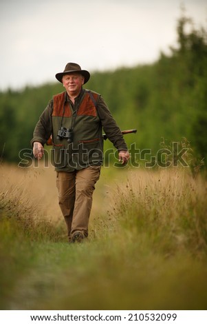 hunter with his rifle in spring forest, hunter holding a rifle and  waiting for prey, hunter shooting, gamekeeper on the walk