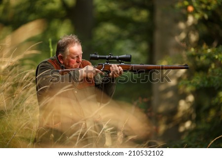 hunter with his rifle in spring forest, hunter holding a rifle and  waiting for prey, hunter shooting