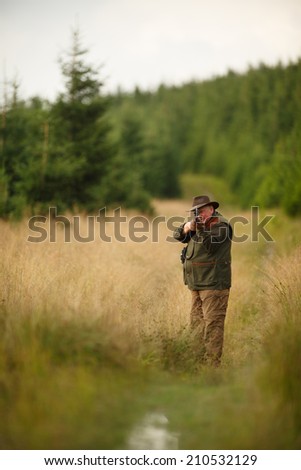 hunter with his rifle in spring forest, hunter holding a rifle and  waiting for prey, hunter shooting