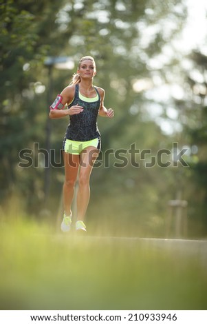 Young lady running. Woman runner running through the spring park road. Workout in a Park. Beautiful fit Girl. Fitness model outdoors. Weight Loss