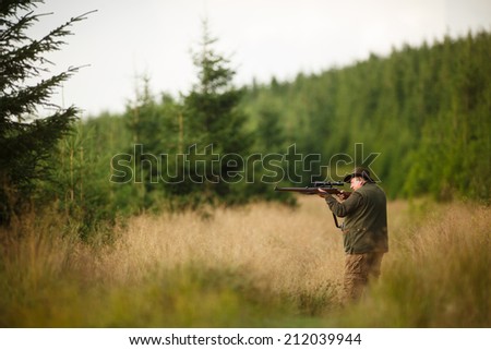 hunter with his rifle in spring forest, hunter holding a rifle and waiting for prey, hunter shooting, on the walk in forest