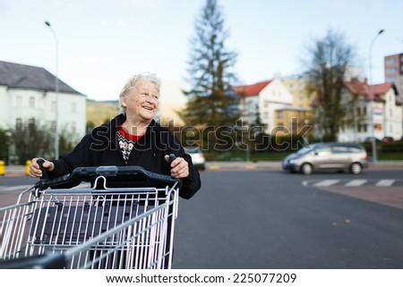 Elderly woman with shopping cart, grocery store/supermarket