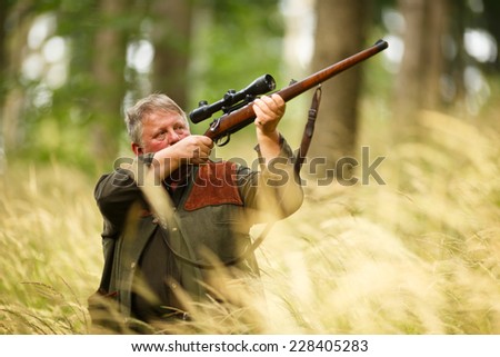 hunter with his rifle in spring forest, hunter holding a rifle and waiting for prey, hunter shooting and aiming