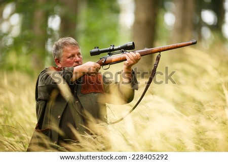 hunter with his rifle in spring forest, hunter holding a rifle and waiting for prey, hunter shooting and aiming