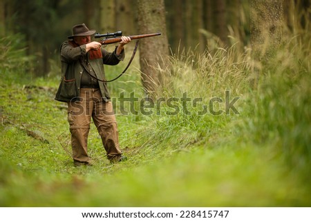 hunter with his rifle in spring forest, hunter holding a rifle and waiting for prey, hunter shooting