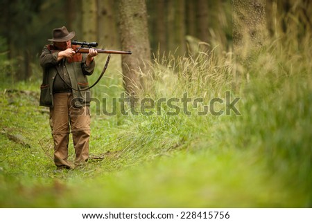 hunter with his rifle in spring forest, hunter holding a rifle and waiting for prey, hunter shooting