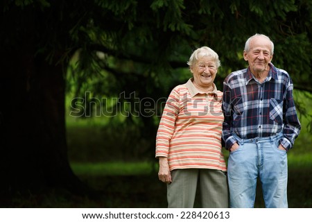 Happy senior couple looking at camera and laughing, Senior woman hugging her partner on a sunny day, Smiling Caucasian older couple embracing