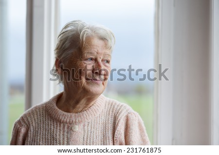 Portrait of Elderly woman looking out window, Grandmother smiling