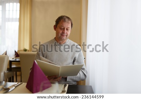 Attractive man in a restaurant looking at the menu. Restaurant concept. Portrait of the smiling successful man at restaurant.