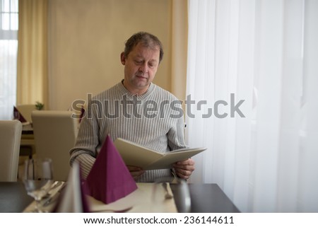 Attractive man in a restaurant looking at the menu. Restaurant concept. Portrait of the smiling successful man at restaurant.
