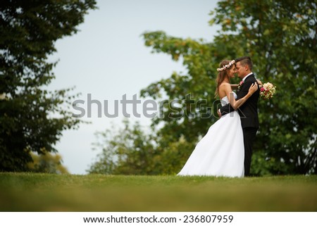 Beautiful wedding couple. Bride and groom. Beautiful young loving couple hugging and looking at each other while standing outdoors. Bride and Groom at wedding day walking Outdoors on spring nature.