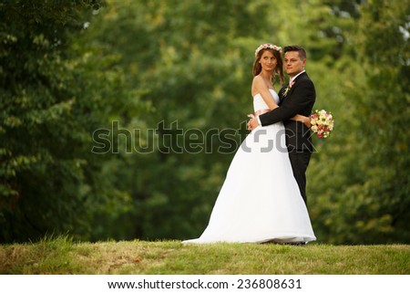Beautiful wedding couple. Bride and groom. Beautiful young loving couple hugging and looking at each other while standing outdoors. Bride and Groom at wedding day walking Outdoors on spring nature.
