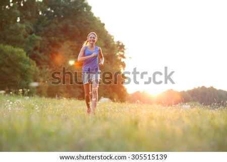 Young lady running. Woman runner running through the spring meadow. Workout in a nature. Beautiful fit Girl. Fitness model outdoors. Weight Loss. Beautiful sunset.