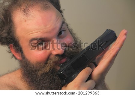 A balding bearded man mugs for the camera while displaying his pistol