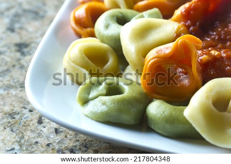 tri-colored tortellini pasta with red tomato sauce and parsley